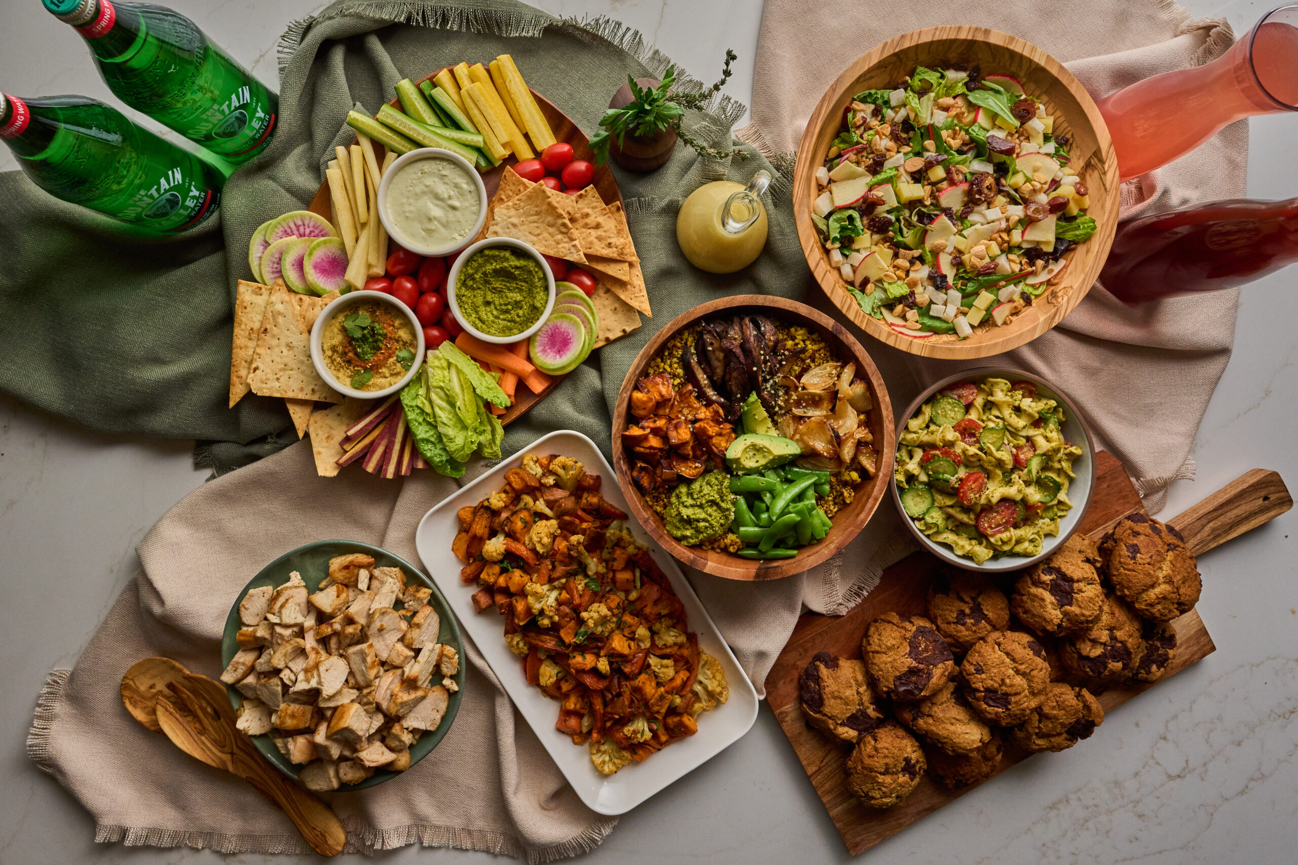 A person carrying a True Food Kitchen catering bag filled with fresh salads and side dishes, showcasing the convenience and variety of the catering options available.