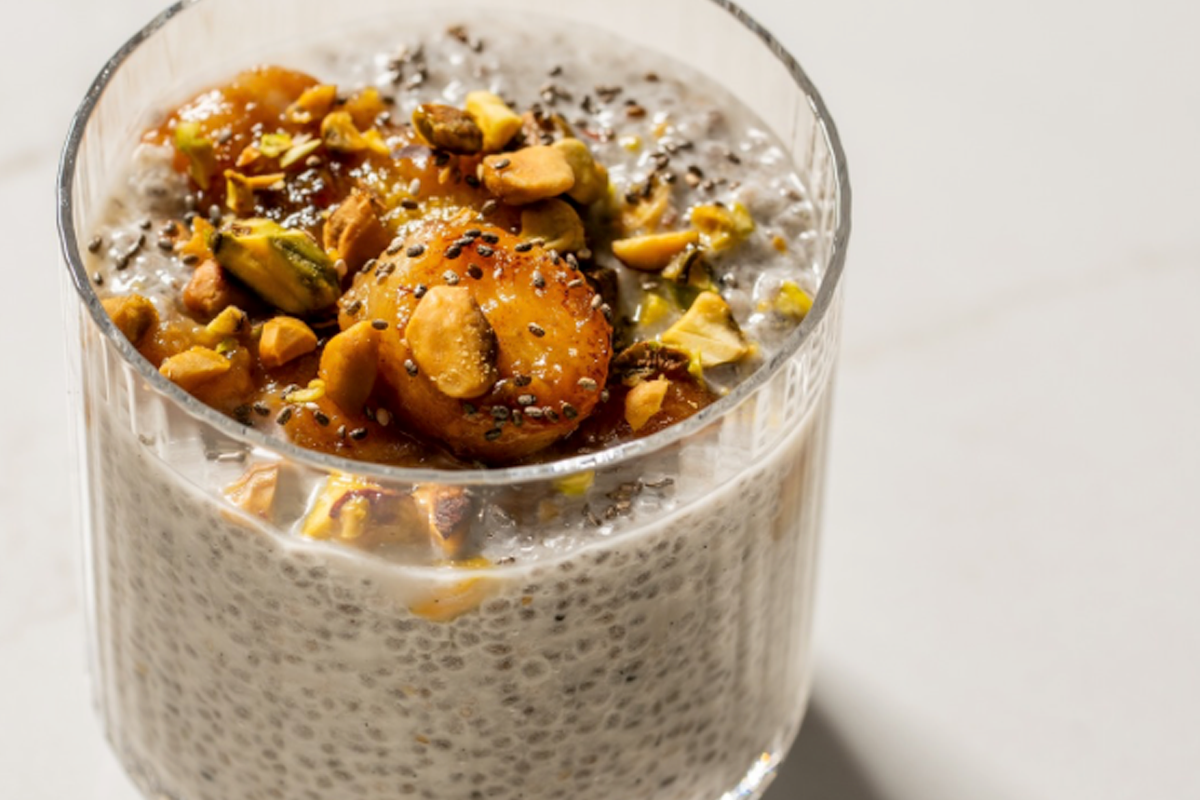 A glass of chia pudding topped with caramelized bananas and chopped nuts, set on a light background, creating a healthy, delicious treat.