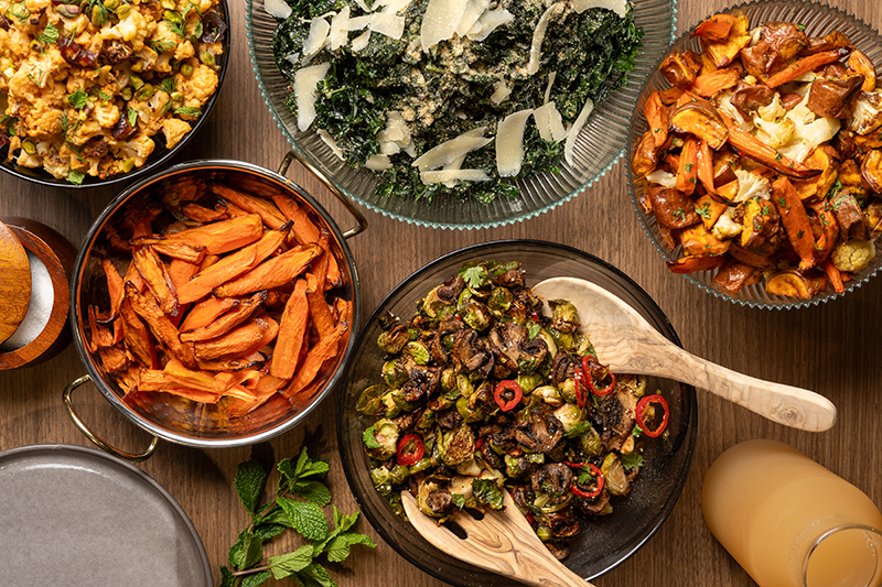 A person carrying a True Food Kitchen catering bag filled with fresh salads and side dishes, showcasing the convenience and variety of the catering options available.