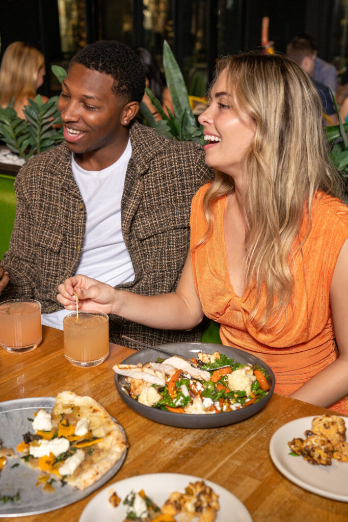 An assortment of dishes from True Food Kitchen's menu, including colorful salads, pizzas, and other fresh items, all beautifully arranged on wooden boards and plates.